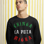 Young man wearing a Chinga La Migra Mexico Hoodie & Sweatshirt, featuring bold protest text in blackletter style, embodying a powerful anti-ICE message, standing against a striped background.