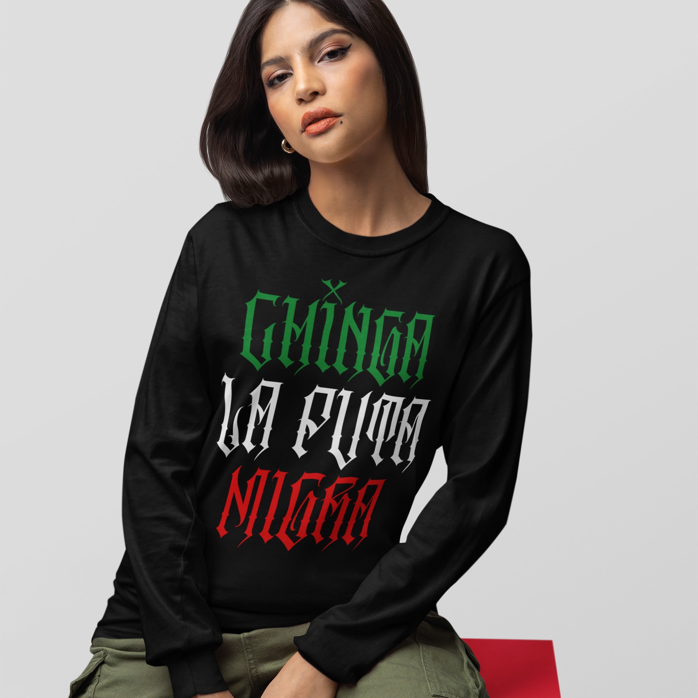 Young woman wearing a Chinga La Migra Mexico T-shirt featuring gothic-style lettering in Mexican flag colors; embodies cultural pride and resistance against anti-immigrant systems. Paired with olive-green cargo pants.