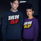 Two young adults wear Minnesota As Fuck Anti-Fascist T-shirts, showcasing bold MN AF text. The man sports a navy tee; the woman, a purple one, reflecting a defiant, expressive style.