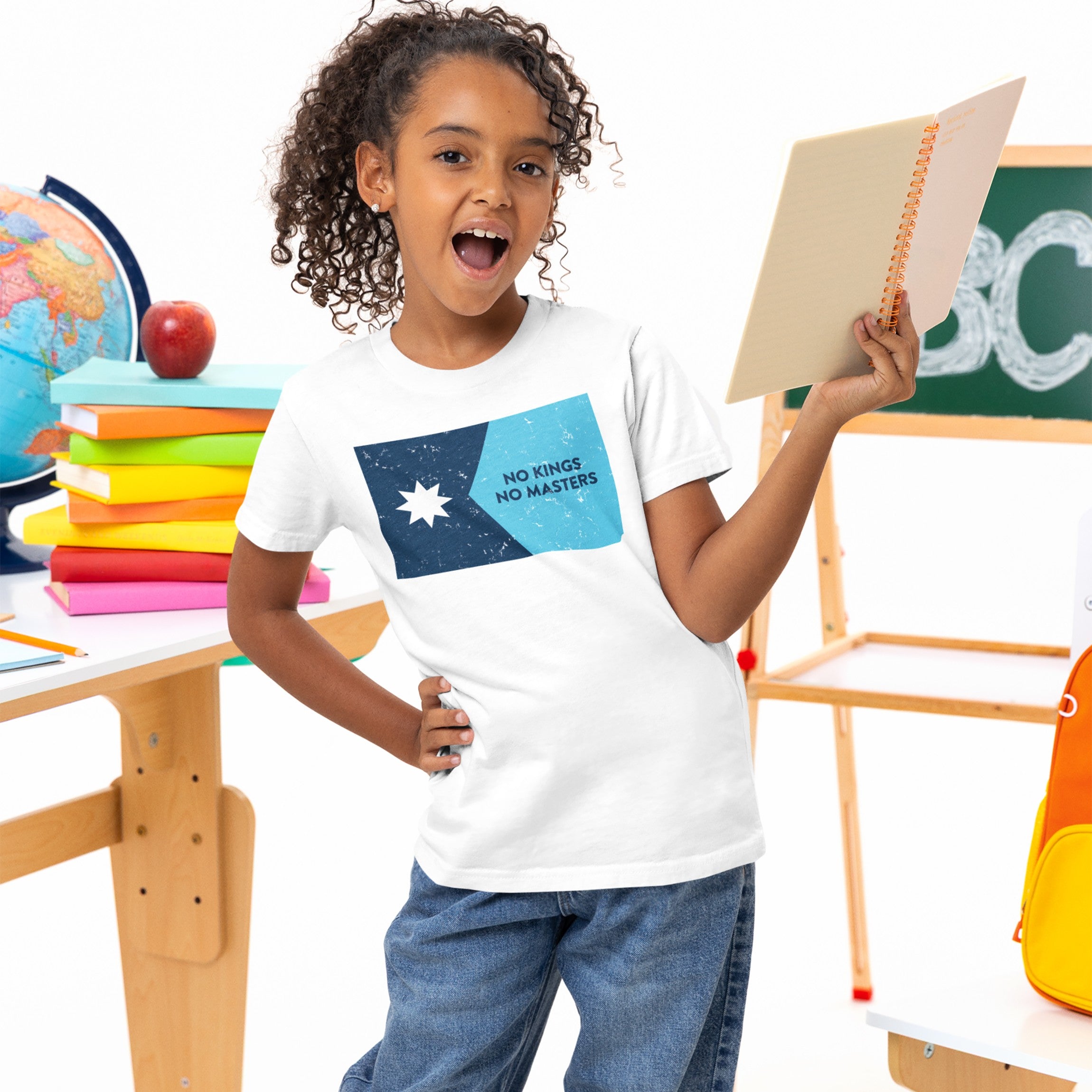 Young girl presenting in a classroom, wearing the Minnesota No Kings Flag Shirt with a blue flag motif and NO KINGS NO MASTERS text, symbolizing resistance and freedom.