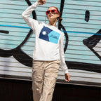 Person wearing the Minnesota No Kings No Masters Flag Shirt, featuring a two-tone blue graphic and slogan, stands before a graffiti backdrop, embodying a rebellious streetwear style against authoritarianism.