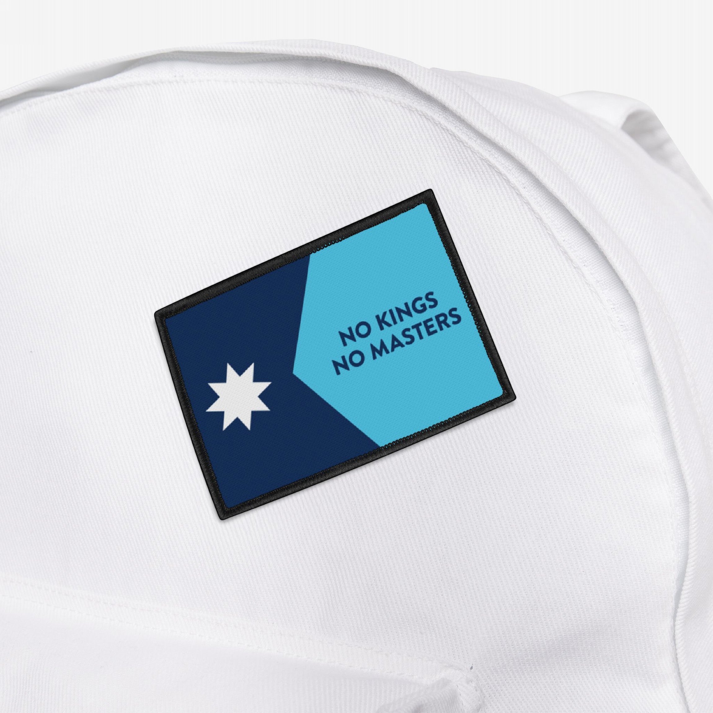 Minnesota Flag No Kings Patch on a white backpack, featuring a blue star and the slogan “NO KINGS NO MASTERS,” symbolizing autonomy and defiance with bold, contrasting colors.