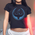 Minnesota Rebel Alliance Women's Baby Tee with a loon logo in a blue circle, worn slightly cropped. The tee symbolizes resistance and equality, aligning with the store's commitment to social justice.