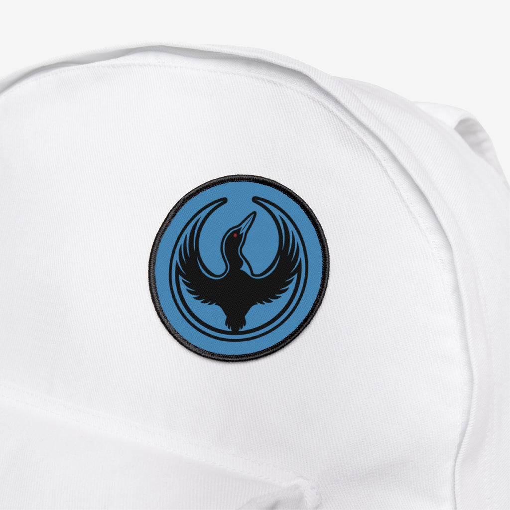 Minnesota Rebel Alliance Patch on a white fabric bag, featuring a blue circle with a black loon and red eye, symbolizing resistance and equality. Perfect for expressing support for immigrant rights.