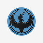 Minnesota Rebel Alliance Sticker featuring Bernie Anderson’s stylized loon logo, a black bird in flight on a blue circular emblem, symbolizing resistance and immigrant rights advocacy. Available in 3” or 5” vinyl sizes.