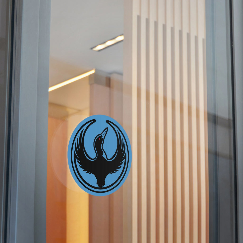 Minnesota Rebel Alliance Sticker featuring a stylized black loon on a blue circular decal, affixed to a glass partition. Available in 3 and 5 sizes, symbolizing resistance and immigrant rights.