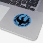 Close-up of a silver laptop featuring the Minnesota Rebel Alliance Sticker, a round blue design with a black loon logo, symbolizing resistance against oppression and support for immigrant rights.