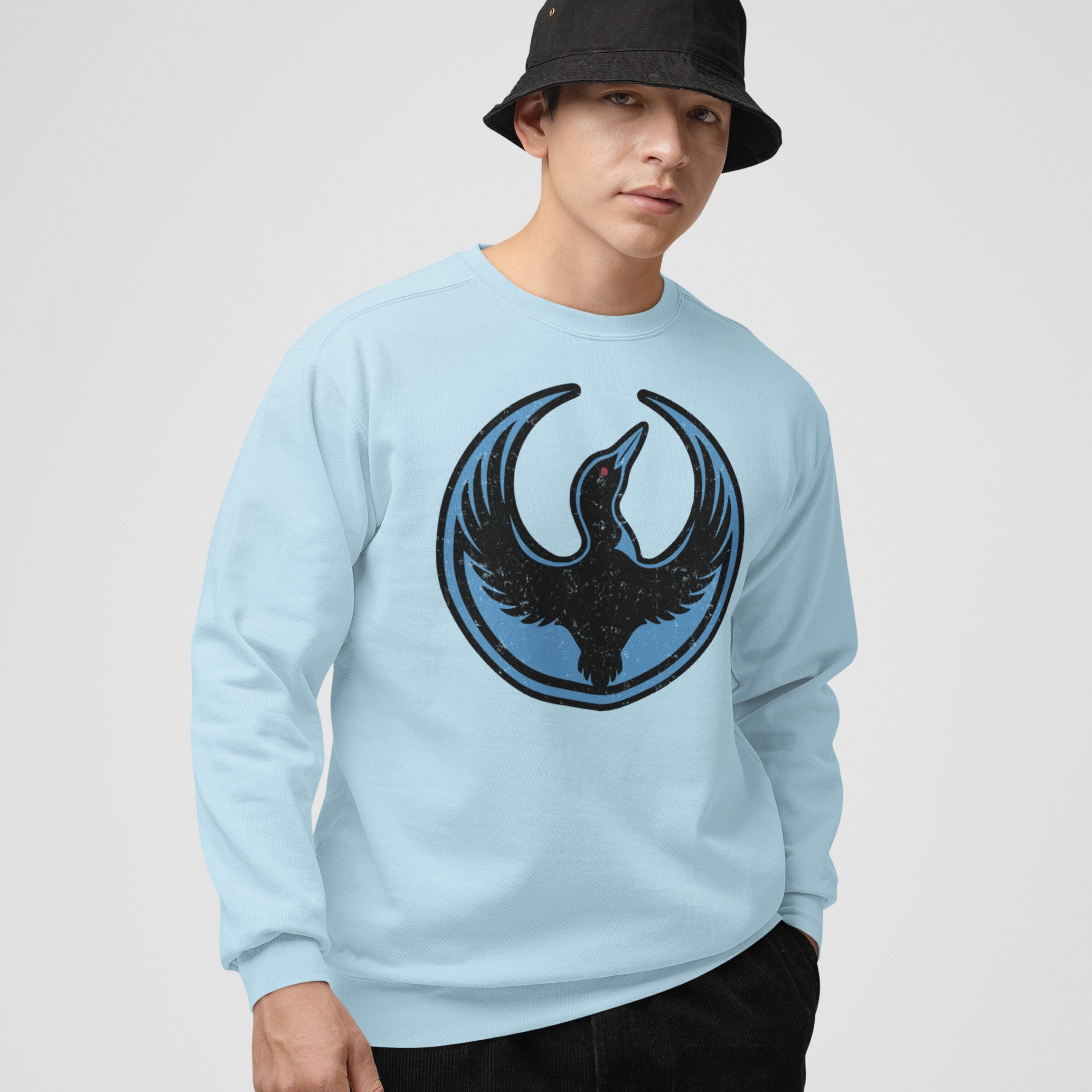 Model wearing the Minnesota Rebel Alliance Hoodie & Sweatshirt, featuring a black loon emblem on pale blue. Styled with a black bucket hat, embodying a spirit of equality and activism.