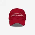 Red dad hat styled to mimic MAGA caps but flipped with embroidered white text "Morons Are Grifting America" — a direct anti-MAGA statement in their own colorway.