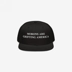 Black snapback hat with flat brim and white embroidered text "Morons Are Grifting America," a bold anti-MAGA message on structured headwear.