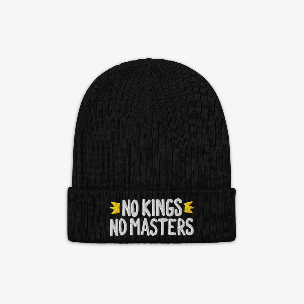 The No Kings No Masters Hat features a black rib-knit design with a fold-over cuff, showcasing the slogan “NO KINGS NO MASTERS” in white, flanked by yellow crown motifs.