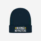 No Kings No Masters Hat: Dark navy-blue ribbed knit beanie with “NO KINGS NO MASTERS” embroidered in white, accented by yellow arrows on the cuff, symbolizing defiance and individuality.