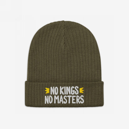 The No Kings No Masters Hat is an olive-green, ribbed knit beanie with a folded cuff, featuring white embroidered text and two yellow crown motifs, embodying rebellious style and anti-authoritarian sentiment.
