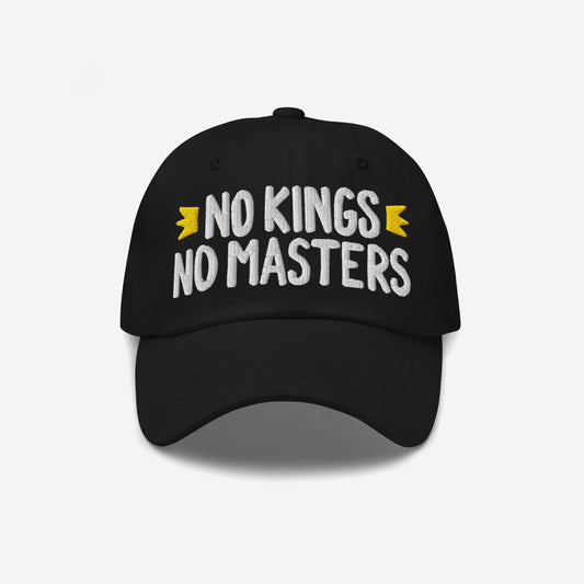 Black cap with bold white NO KINGS NO MASTERS embroidery and yellow crown accents, embodying rebellious spirit. Available in various styles, supporting Amnesty International.