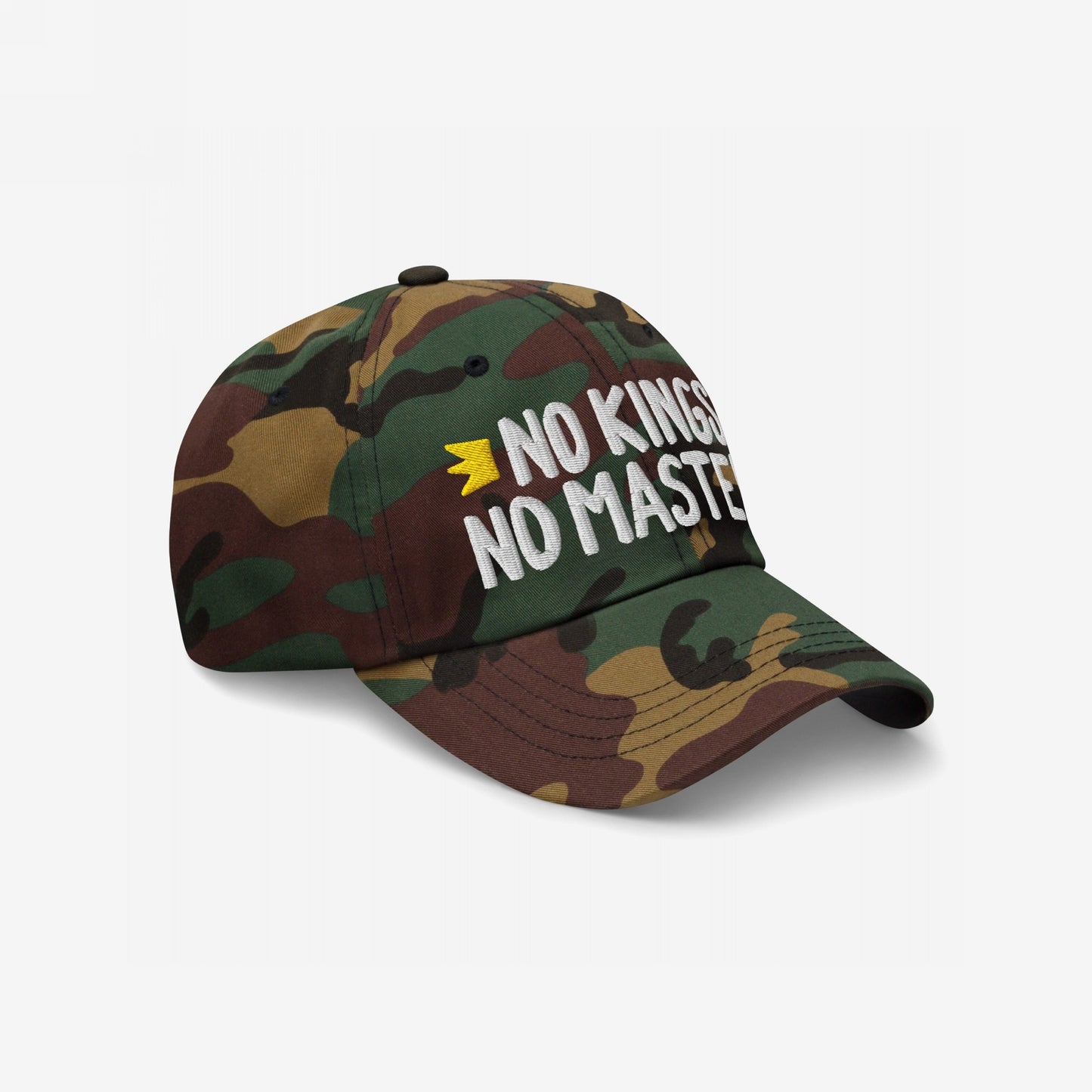 No Kings No Masters Hat featuring a woodland camouflage design with white embroidered slogan and yellow crown, embodying rebellious spirit and solidarity with causes like Amnesty International.