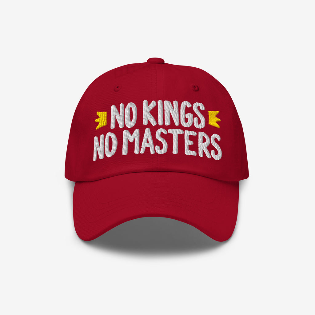 No Kings No Masters Hat: A red unstructured cap with “NO KINGS NO MASTERS” in bold white embroidery, flanked by yellow motifs, representing rebellion and individuality.
