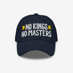 Navy-blue cap with NO KINGS NO MASTERS in white, accented by gold crowns. An anti-establishment statement piece for those who challenge authority and support equality.