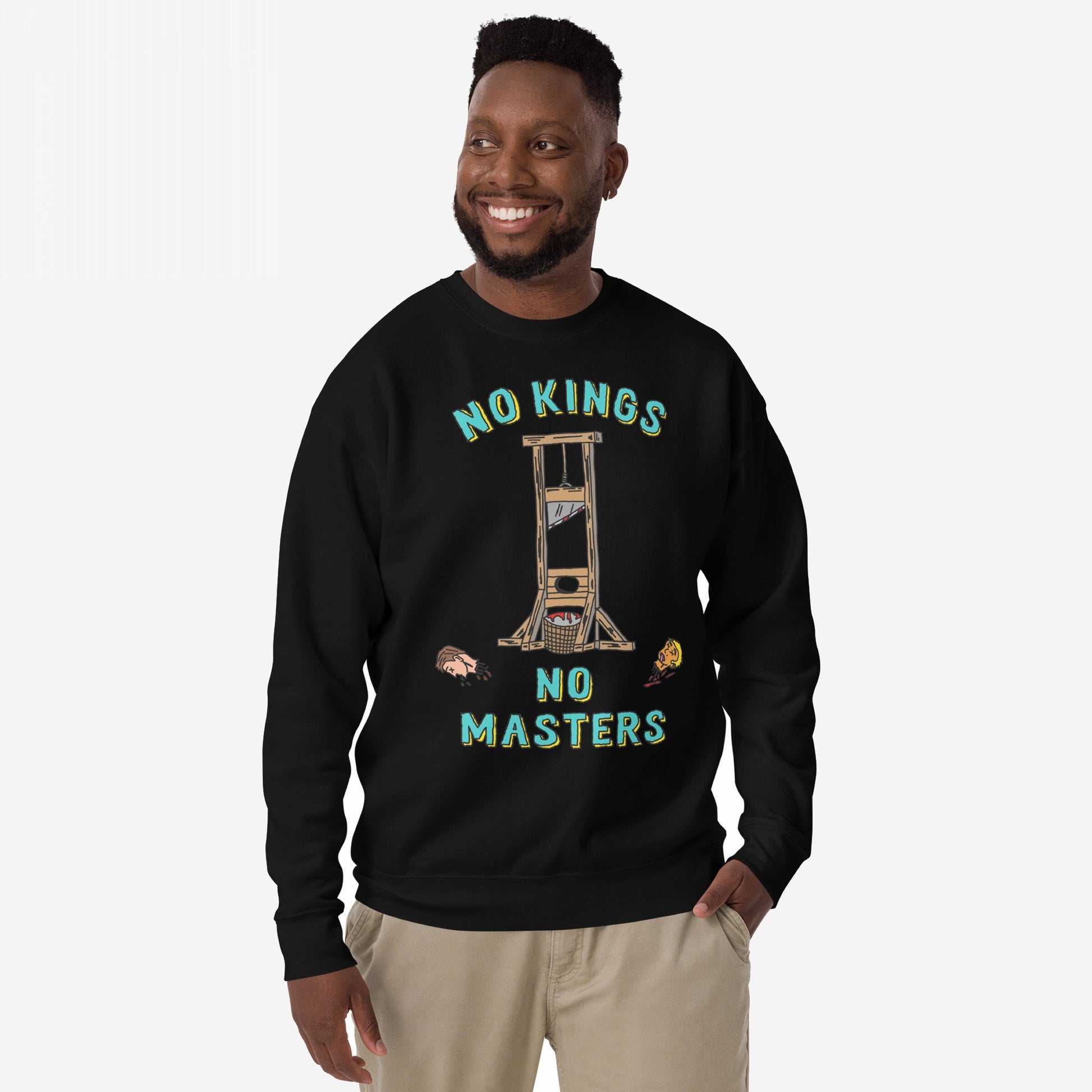 Man in a black No Kings No Masters Sweatshirt, featuring a bold guillotine graphic with severed heads and the slogans “NO KINGS” and “NO MASTERS”, embodying rebellion and rejection of authoritarianism.