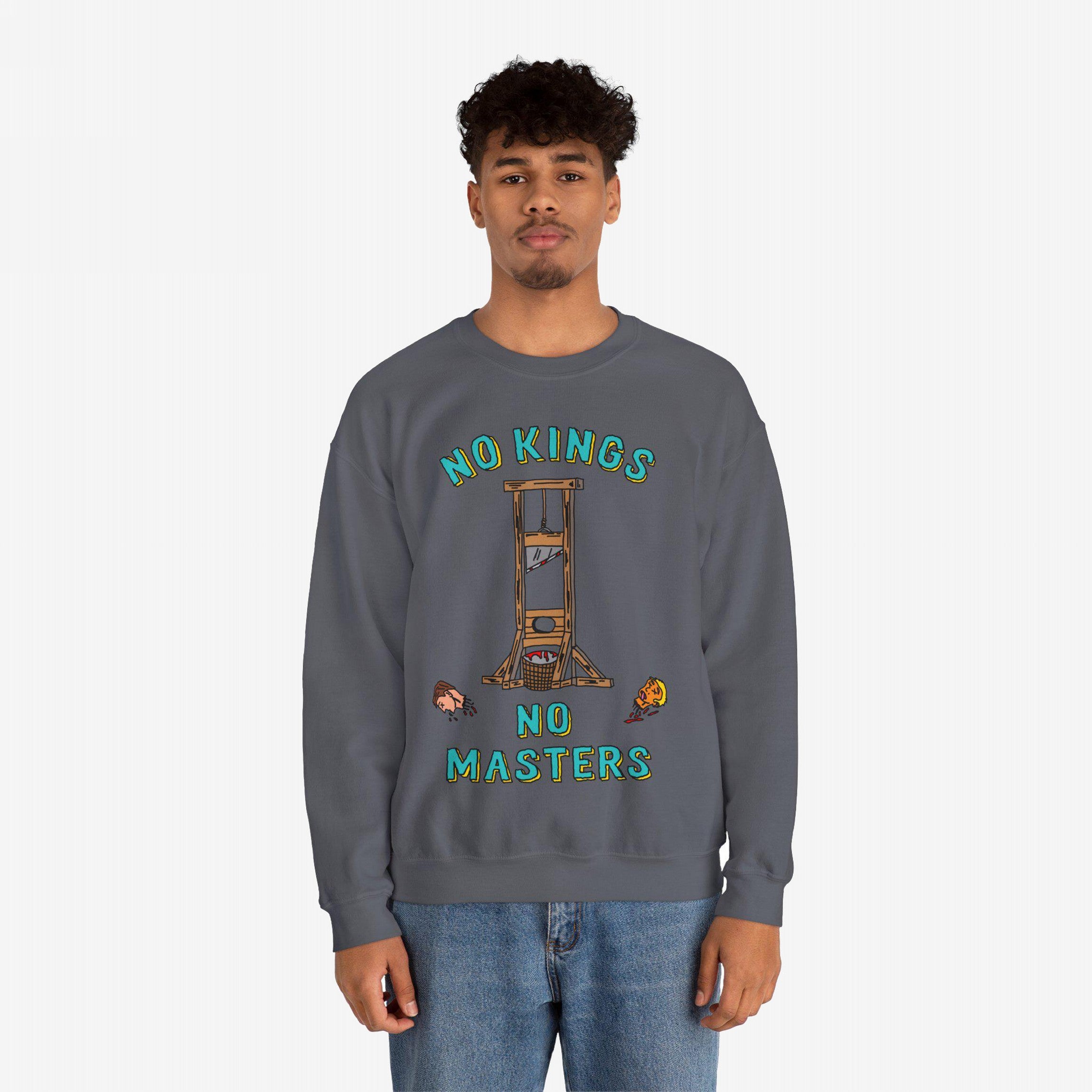Young man wearing a No Kings No Masters sweatshirt featuring a cartoon-style guillotine and dripping severed heads, symbolizing anti-authoritarian defiance against fascism and oligarchy. Paired with casual blue jeans.