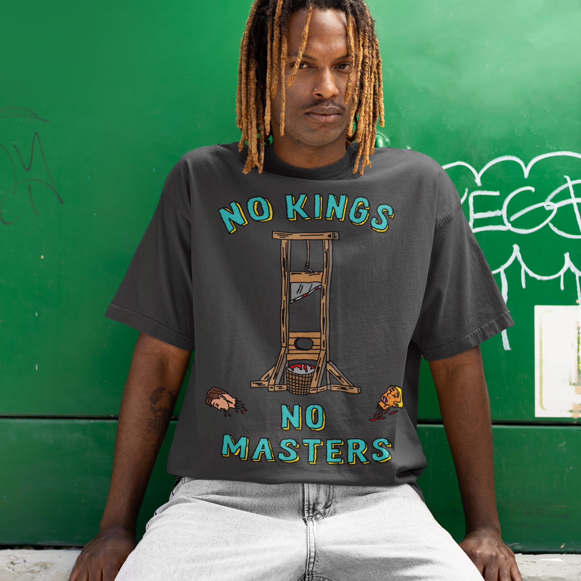 Person with dreadlocks wearing the No Kings No Masters Shirt featuring a bold guillotine graphic and severed heads, symbolizing anti-authoritarian defiance and resistance. Ideal for those challenging authority.