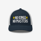 No Kings No Masters Hat featuring bold white embroidery on a navy cap with white mesh, symbolizes rebellion and individuality with yellow crown accents, embodying a defiant spirit against authority.