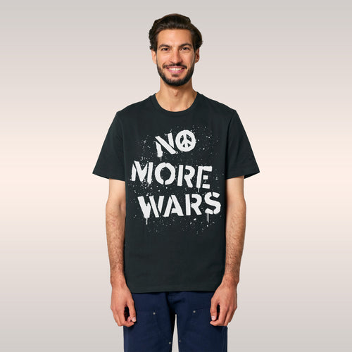 A young adult with longish hair and light stubble wears the No More Wars Shirt, featuring a peace-sign icon and the phrase NO