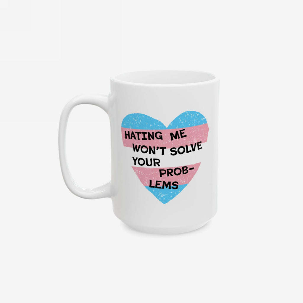 No Trans Hate Mug features a white ceramic design with a heart graphic in transgender-pride colors, overlaid with the phrase “HATING ME WON’T SOLVE YOUR PROB-LEMS.” Perfect for supporting trans visibility and strength.