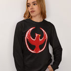 Person wearing the Northern Cardinal Rebel Alliance T-shirt, featuring a bold red phoenix emblem with wings forming a circle on a black long-sleeve shirt, symbolizing resistance and community defense.