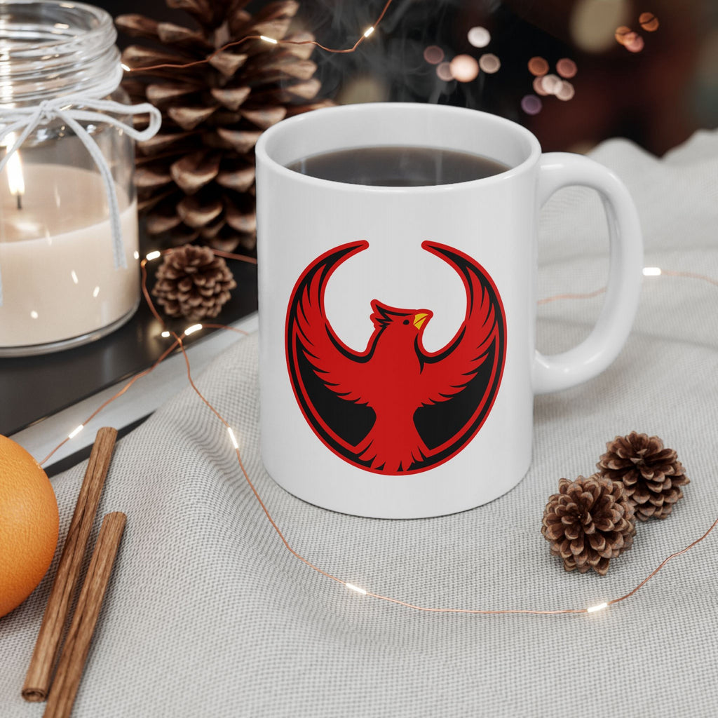 St. Louis Rebel Alliance Mug amidst a festive scene with pinecones, cinnamon sticks, and fairy lights, showcasing a red phoenix emblem against a black circle, symbolizing anti-fascist protest and community strength.