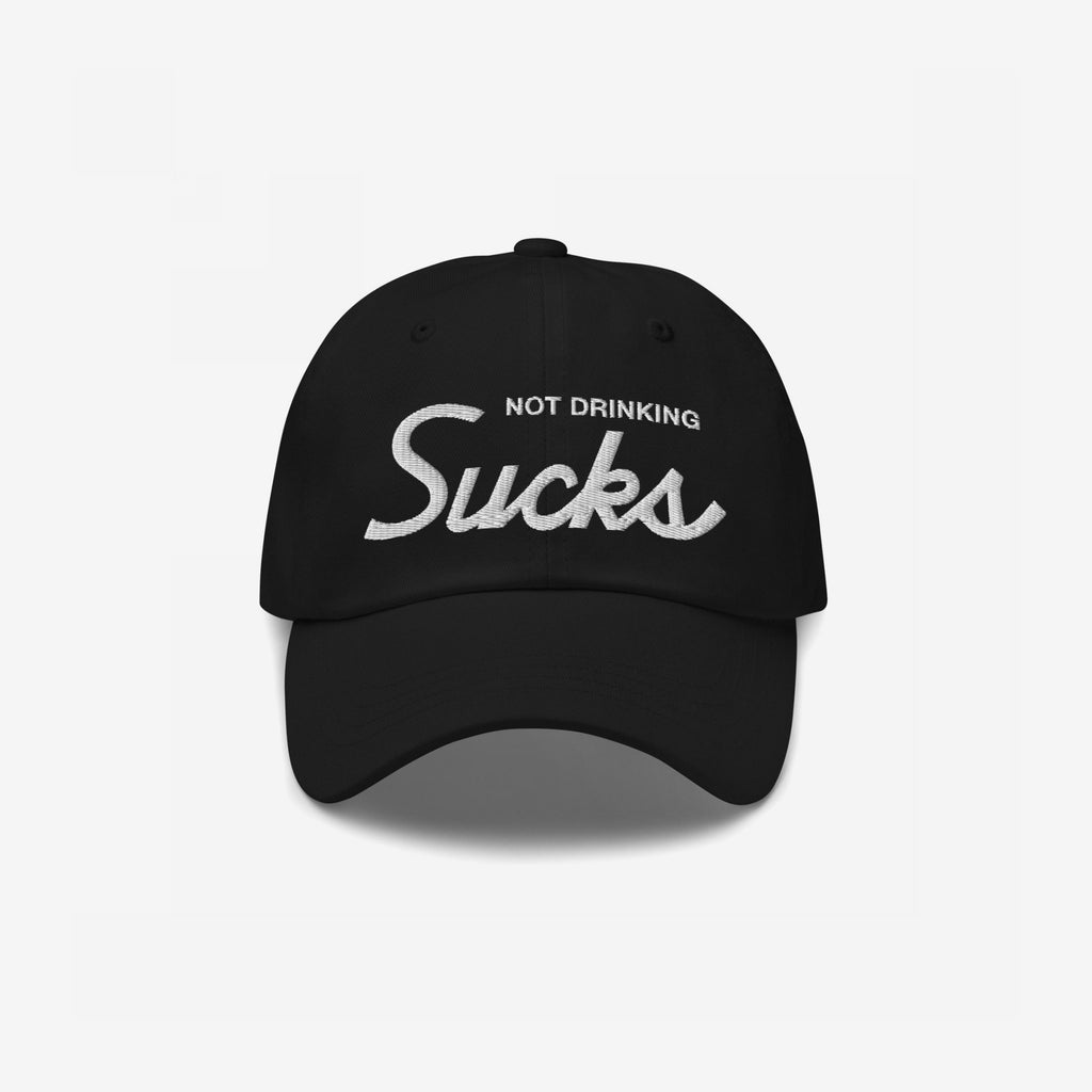 Not Drinking Sucks Hat features bold, white embroidered text on a black baseball cap, capturing a playful and honest party spirit.