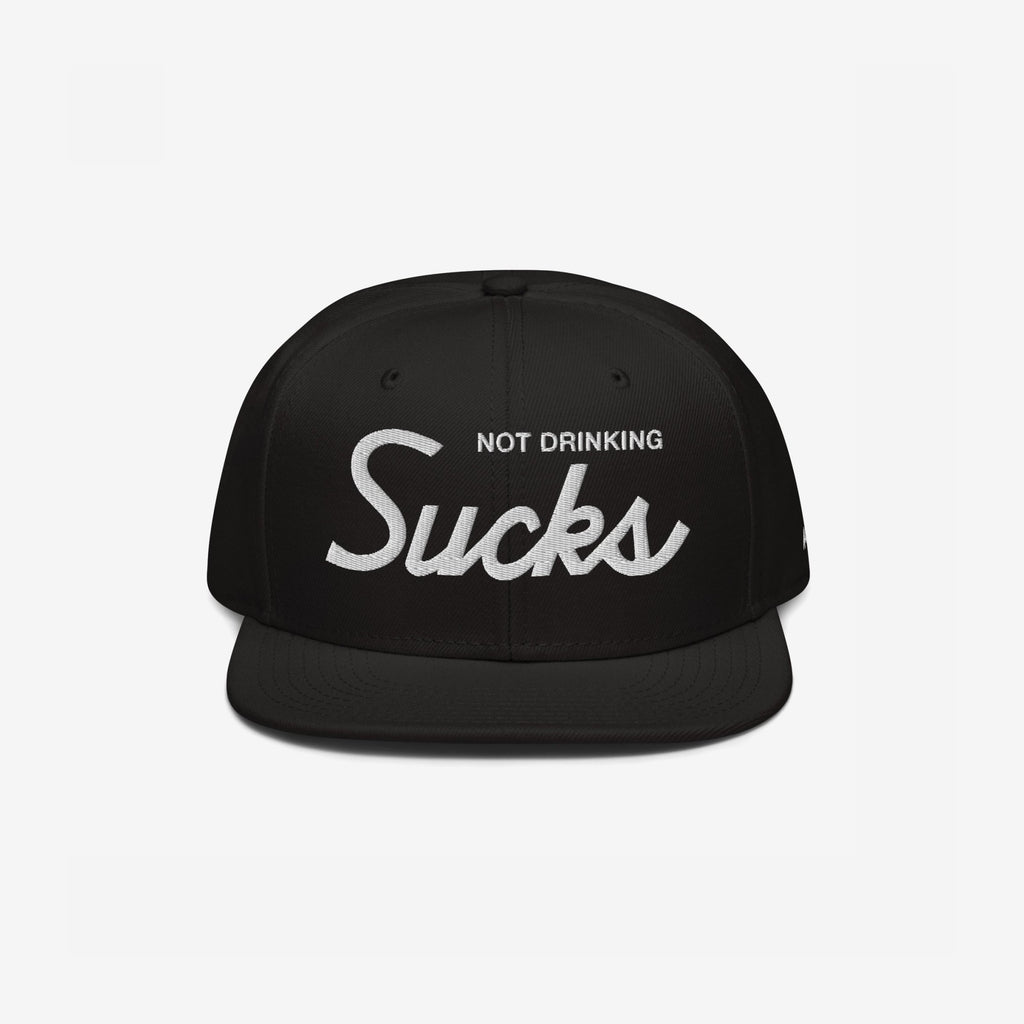 Not Drinking Sucks Hat with white embroidery on the front panel, featuring a bold retro script. A playful statement piece for parties, embodying a carefree, inclusive vibe. Snapback style, perfect for casual outings.