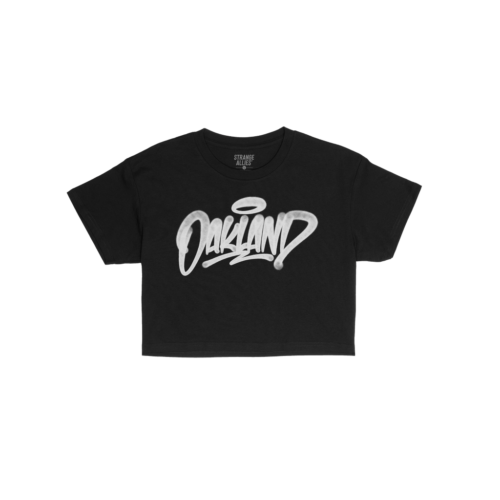 Oakland Handstyle Women's Baby Tee in black features bold, white graffiti-style Oakland script across the chest, embodying ed