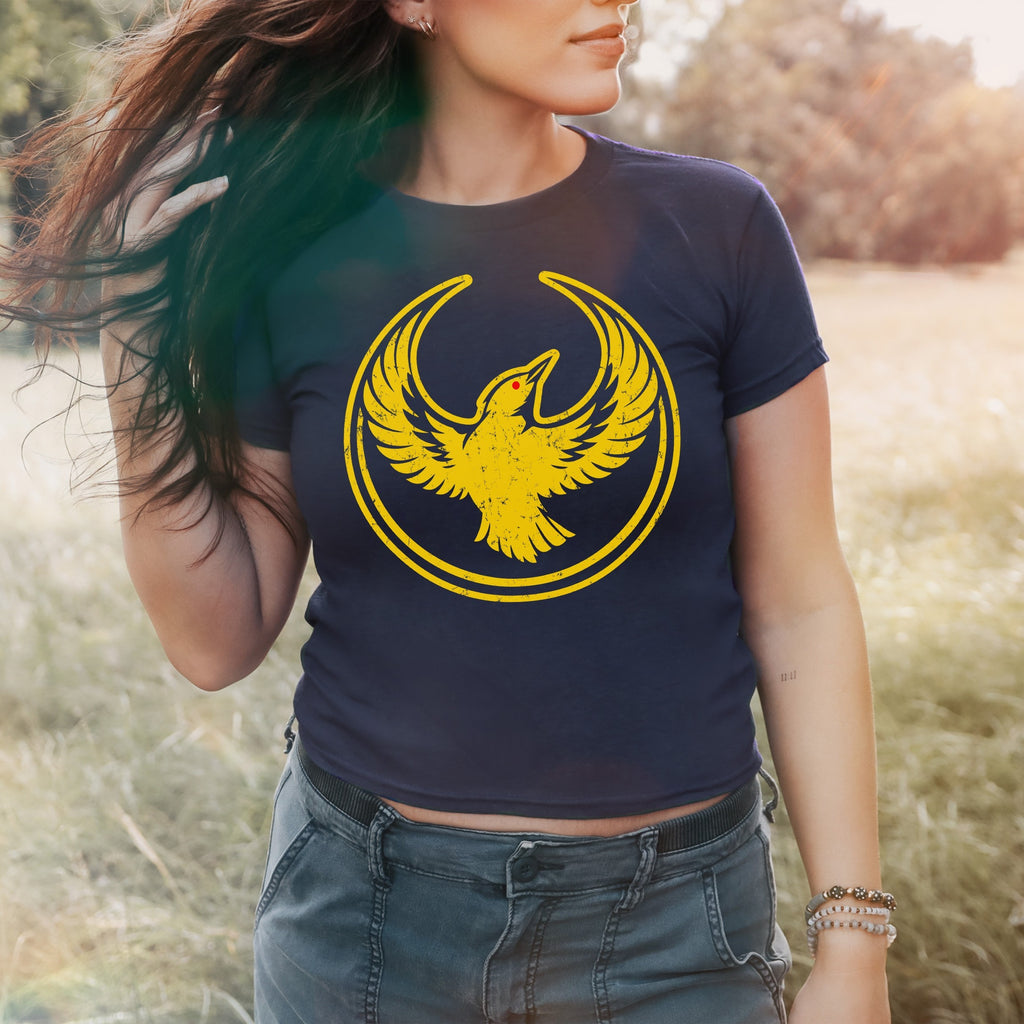 Young person wearing the Oregon Rebel Alliance Women's Baby Tee, featuring a distressed yellow phoenix emblem inside a circular frame, symbolizing activism and Oregon pride.