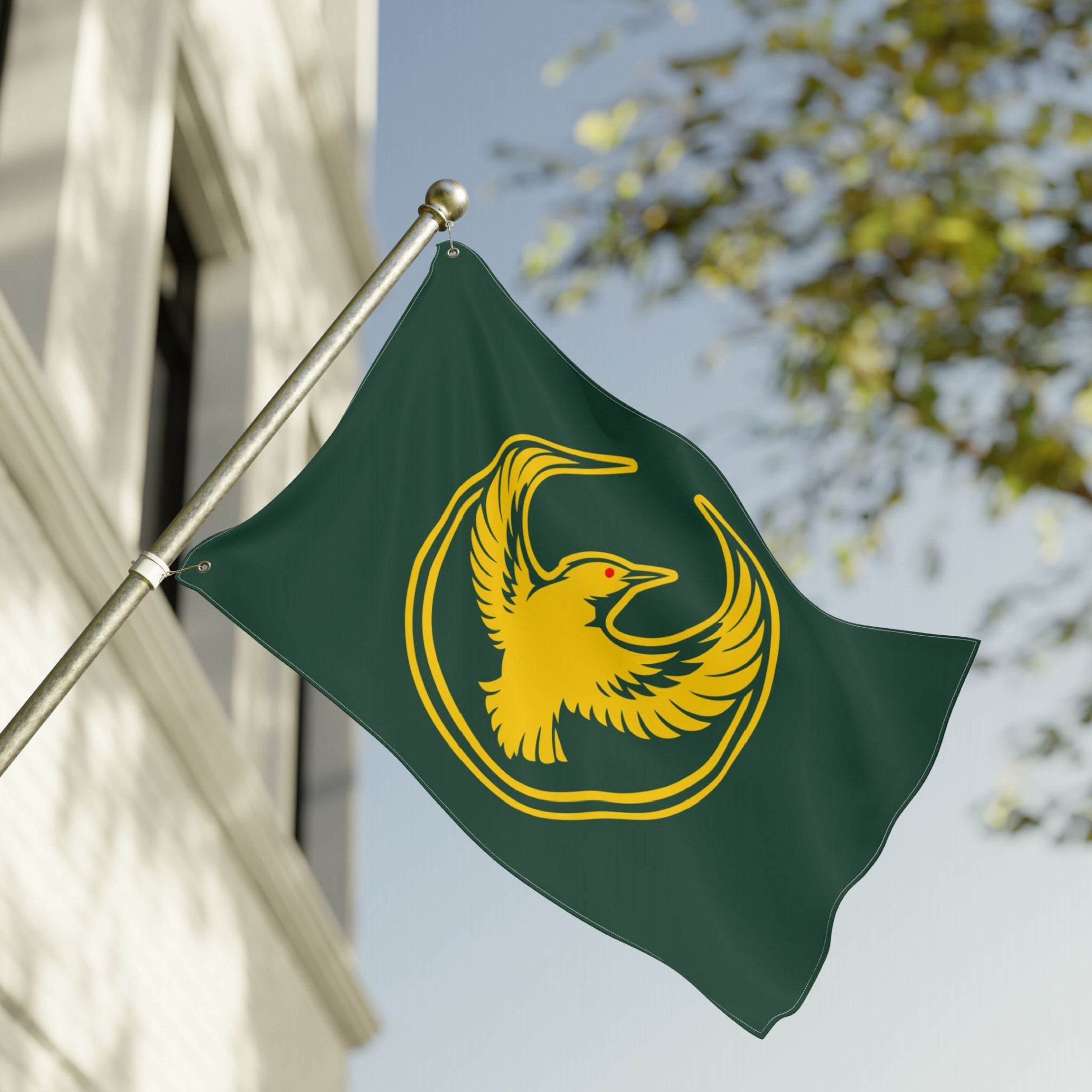 Oregon Rebel Alliance Flag features a golden stylized bird with outstretched wings on a dark green background, symbolizing solidarity and defiance, mounted on a pole against a white building.