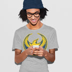 A young person wearing an Oregon Rebel Alliance T-shirt smiles at a smartphone. The shirt features a yellow bird emblem, symbolizing protest and solidarity.