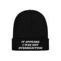 Black rib-knit beanie titled Overreacting Hat, featuring white embroidery on the cuff with the phrase “IT APPEARS I WAS NOT