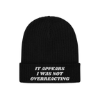 Black rib-knit beanie titled Overreacting Hat, featuring white embroidery on the cuff with the phrase “IT APPEARS I WAS NOT