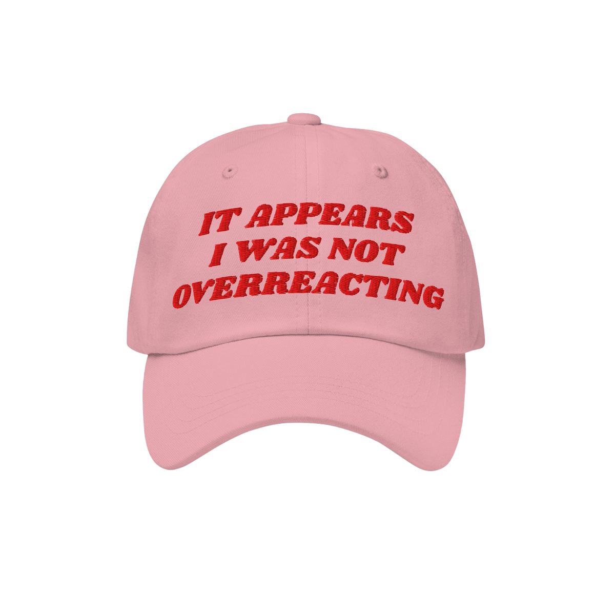 The Overreacting Hat features bold red embroidery on a light pink cap, declaring “IT APPEARS I WAS NOT OVERREACTING,” emb