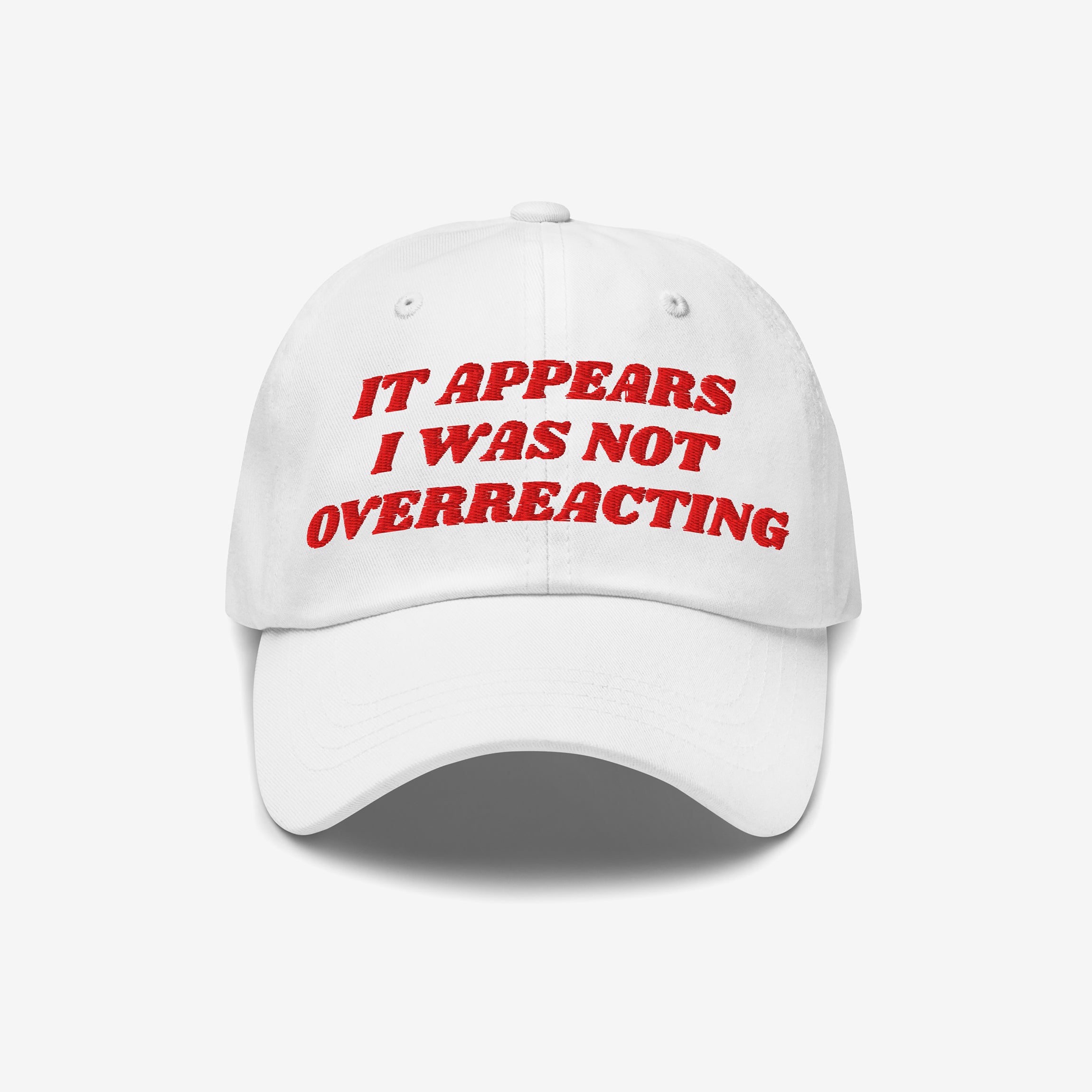 White baseball-style cap with red embroidered text: “IT APPEARS I WAS NOT OVERREACTING.” The Overreacting Hat symbolizes resistance against fascism, crafted for progressive voices.