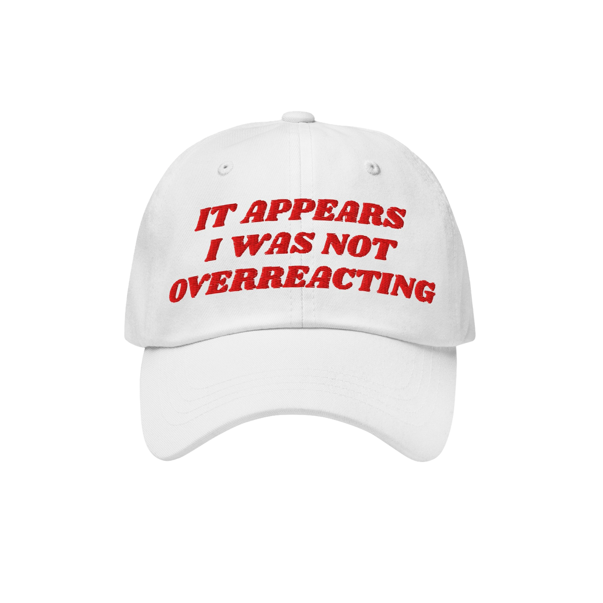 White baseball-style cap with red embroidered text: “IT APPEARS I WAS NOT OVERREACTING.” The Overreacting Hat symbolizes 