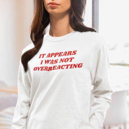 Person wearing the Overreacting T-shirt with bold red text, IT APPEARS I WAS NOT OVERREACTING, holding a takeaway cup lid, embodying unapologetic defiance and truth in a casual indoor setting.