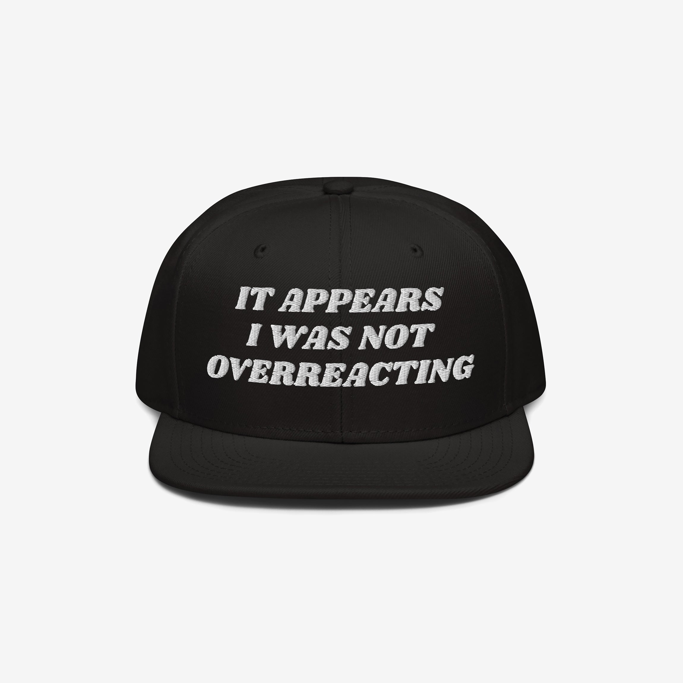 The Overreacting Hat is a black snapback with white embroidery reading It appears I was not overreacting, symbolizing resistance to fascism and supporting progressive values.