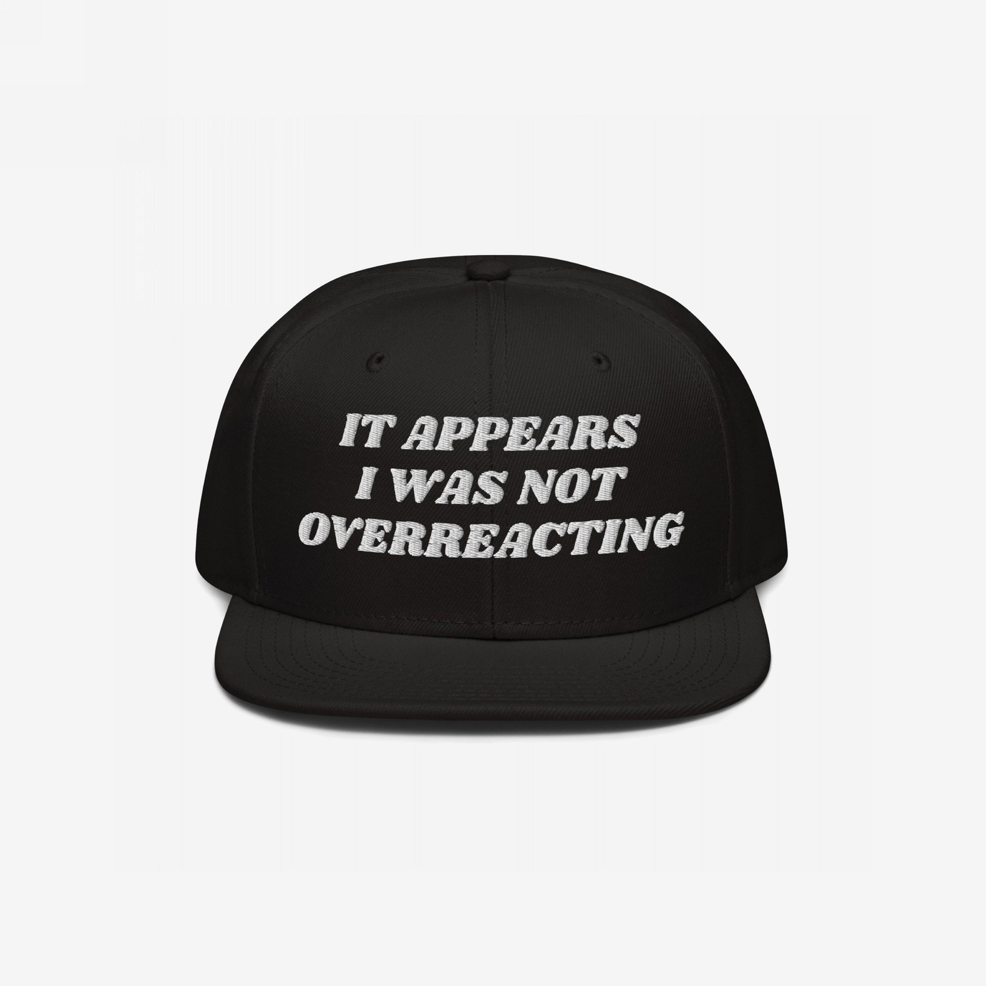 Black flat-bill snapback cap with white embroidered text: “It appears I was not overreacting.” The Overreacting Hat signifies resilience against political gaslighting, supporting progressive voices demanding justice and equality.