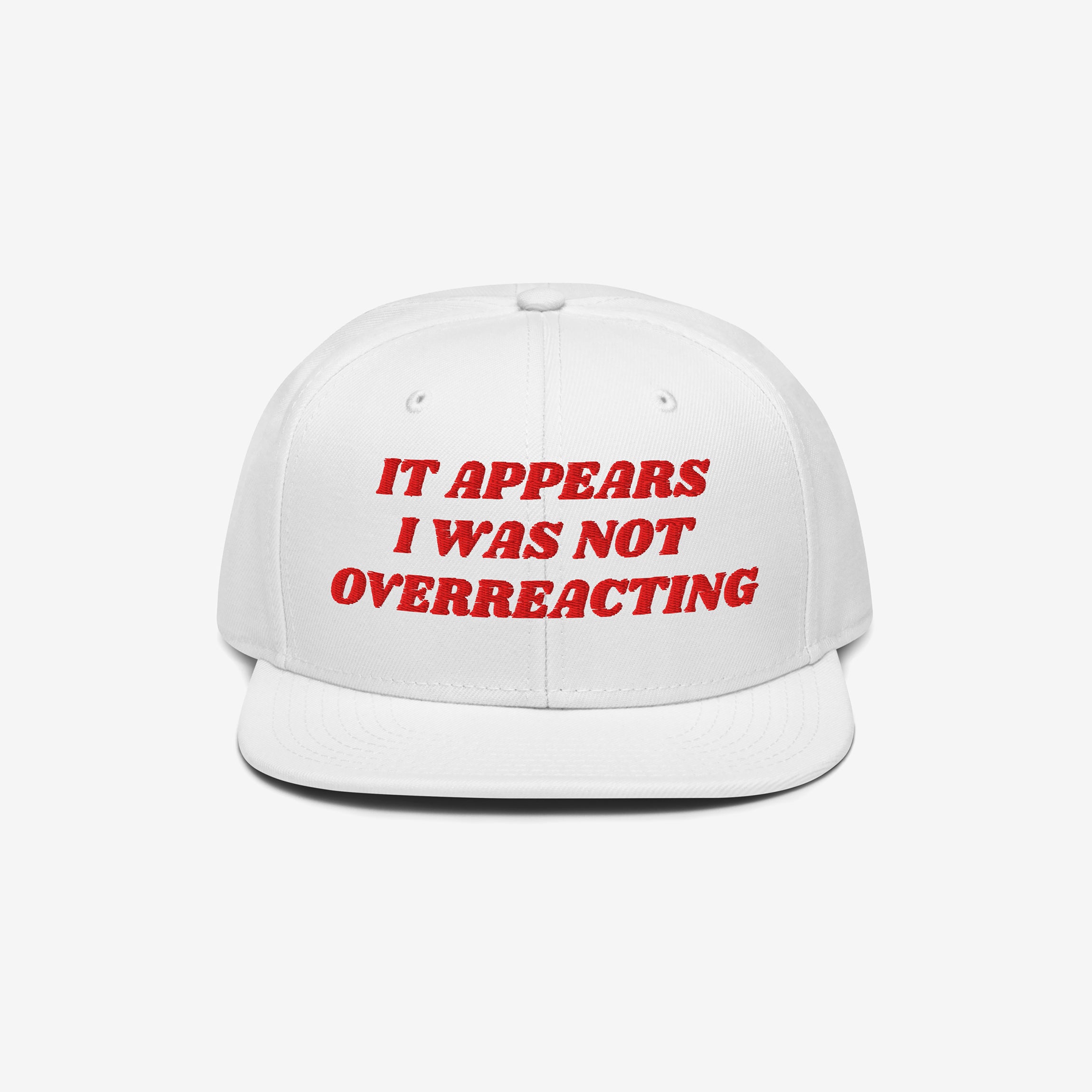 White snap-back cap with red embroidery reading IT APPEARS I WAS NOT OVERREACTING, the Overreacting Hat champions anti-fascist values, crafted for progressives opposing extremism and supporting equality.