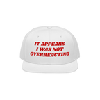 White snap-back cap with red embroidery reading IT APPEARS I WAS NOT OVERREACTING, the Overreacting Hat champions anti-fascis