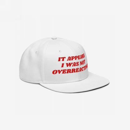 The Overreacting Hat features bold red embroidery stating IT APPEARS I WAS NOT OVERREACTING on a white snapback cap, embodying a fearless stance against political gaslighting and injustice.