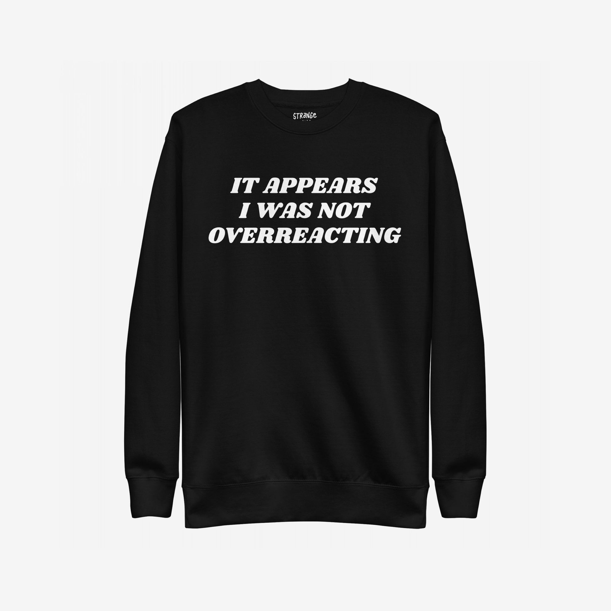 Black crewneck sweatshirt titled Overreacting Hoodie & Sweatshirt features bold white text: IT APPEARS I WAS NOT OVERREACTING, symbolizing resistance and defiance against oppressive systems. Brand label visible inside collar.