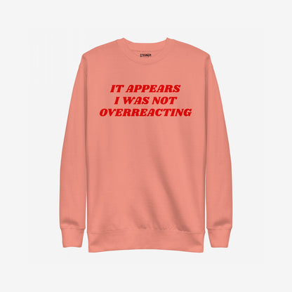 Overreacting Hoodie & Sweatshirt features bold red lettering stating, “IT APPEARS I WAS NOT OVERREACTING,” on a muted coral crewneck, embodying resistance against oppression and supporting equality.