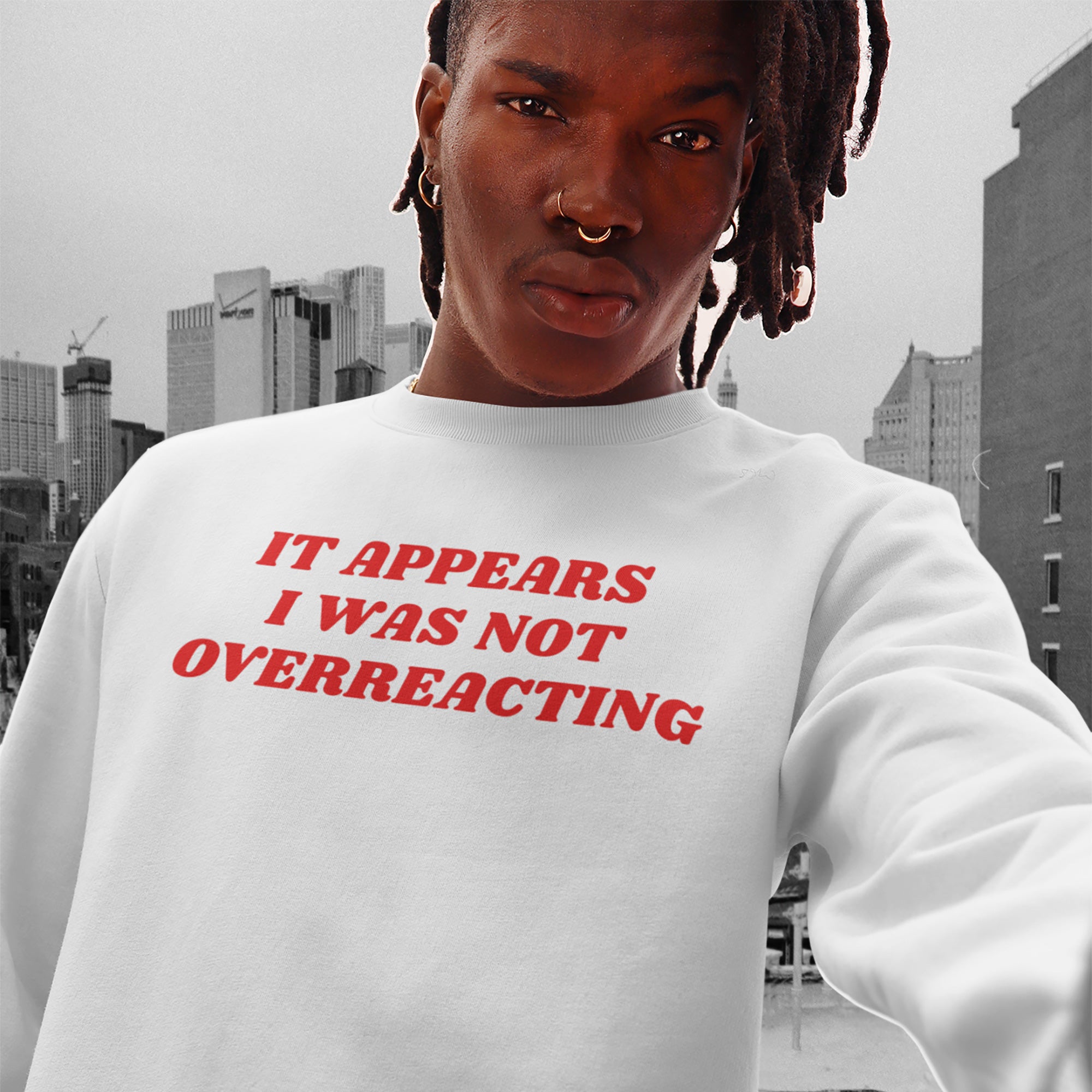 Young person taking a selfie wearing the Overreacting Shirt, a white sweatshirt with bold red text It appears I was not overreacting, against a city skyline, embodying a statement of resistance and activism.