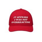 Red trucker-style Overreacting Hat with white embroidered text “IT APPEARS I WAS NOT OVERREACTING,” symbolizing anti-fasc